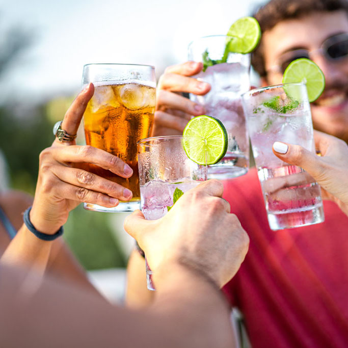 Cheerful Young Friends Toasting with Summer Cocktails - Focus on Clinking Glasses