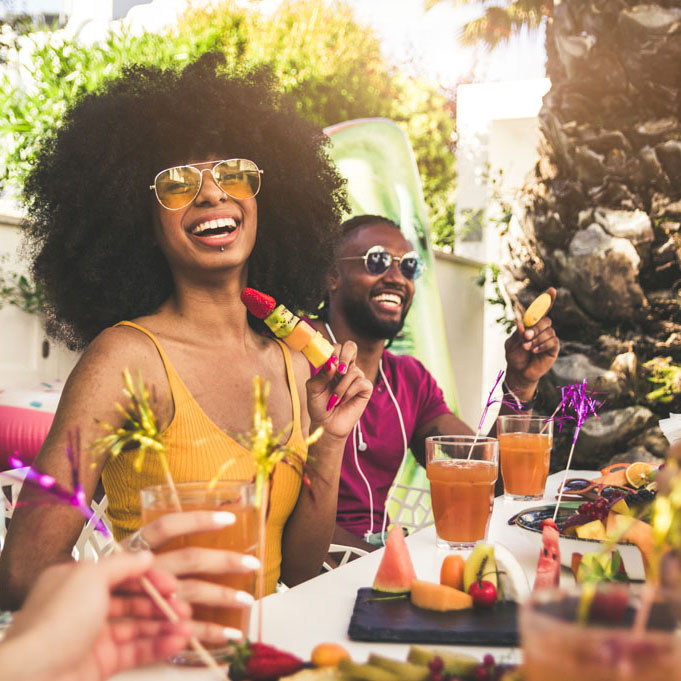 Multiracial group of friends having fun at backyard home party - Young people laughing together drinking cocktails at bar restaurant - Focus on black woman