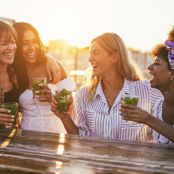 Happy girls having fun drinking cocktails at bar on the beach - Soft focus on center girl face
